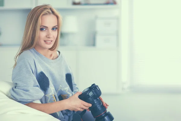Женщина сидит на диване в своем доме с камерой — стоковое фото