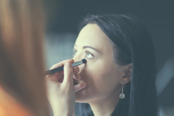 Giovane bella donna che fa il make-up vicino specchio, seduto alla scrivania . — Foto Stock