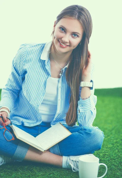 Young woman sitting with book on grass — Stock Photo, Image