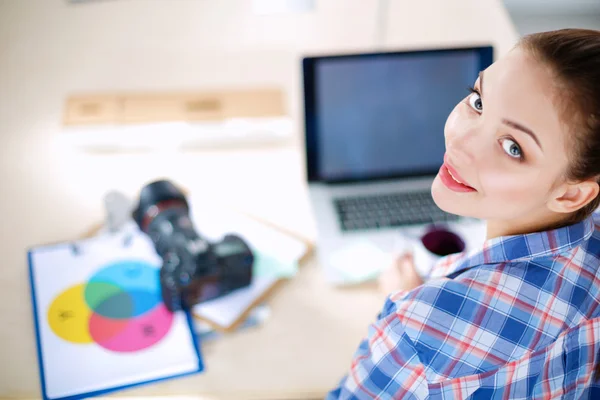 Vrouwelijke fotograaf zittend op het bureau met laptop — Stockfoto