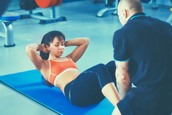 美丽的女人在健身房锻炼与她的教练 — 图库照片