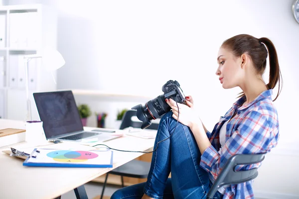 Kvinnlig fotograf sitter på skrivbordet med bärbar dator — Stockfoto