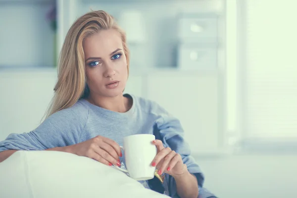 Vrouw zittend op de Bank met kopje in haar handen — Stockfoto