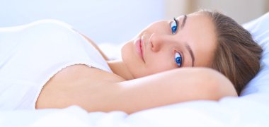 Genç ve güzel bir kadın yatakta yatıyor.