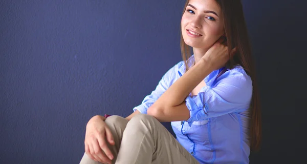 Young woman sitting on the floor near dark wall — Stock Photo, Image