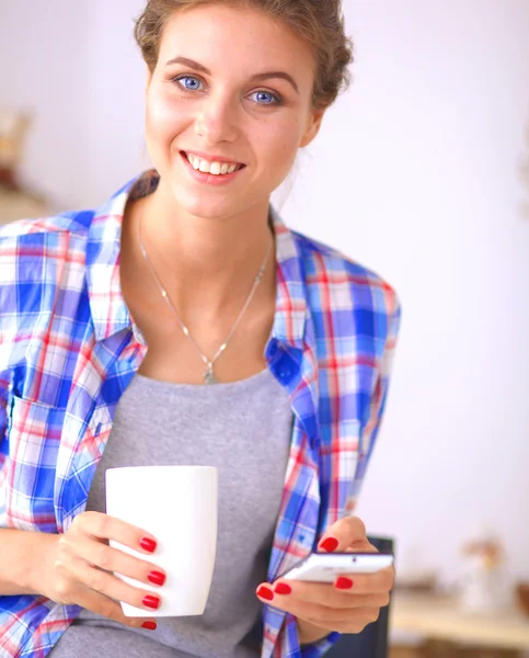 Smiling woman holding her cellphone in the kitchen — Stock Photo, Image