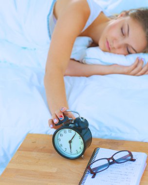 Genç bir kadın sabah alarmını erteliyor.