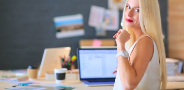 Moda tasarımcıları stüdyoda çalışıyor. Masanın üzerinde oturuyorlar.