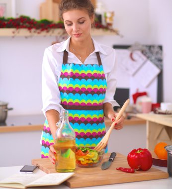 Masanın yanında duran taze salatayı karıştıran genç kadın.