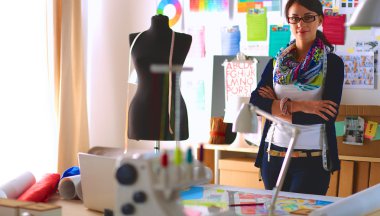 Güzel moda tasarımcısı stüdyoda duruyor.