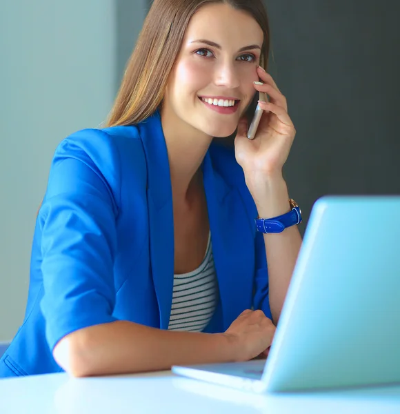 Ritratto di una giovane donna al telefono davanti a un computer portatile . — Foto Stock