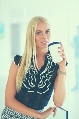 Ofiste bir fincan kahve ayakta tutan işkadını