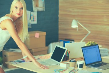 Moda tasarımcıları stüdyoda çalışıyor. Masanın üzerinde oturuyorlar.