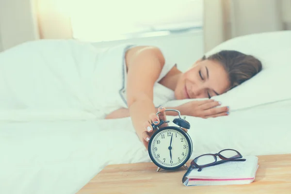 Joven mujer poniendo su despertador apagado en la mañana — Foto de Stock