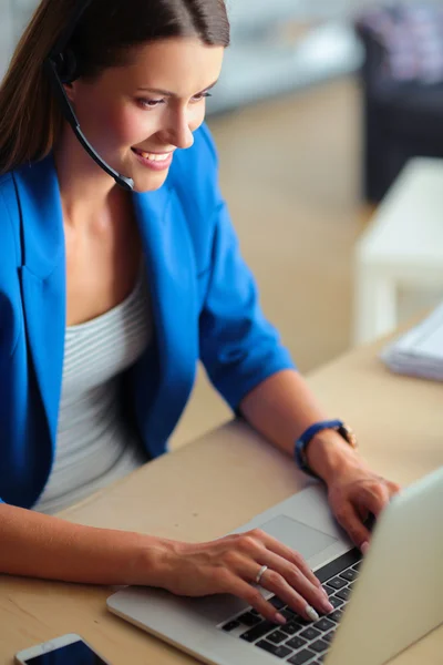 Retrato de mulher de negócios bonita trabalhando em sua mesa com fone de ouvido e laptop — Fotografia de Stock