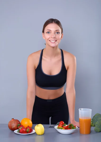 Mulher jovem e bonita de pé perto da mesa com legumes — Fotografia de Stock