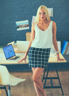 Moda tasarımcıları stüdyoda çalışıyor. Masanın üzerinde oturuyorlar.