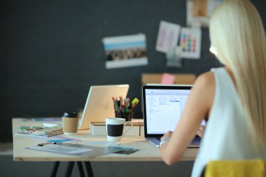 Moda tasarımcıları stüdyoda çalışıyor. Masanın üzerinde oturuyorlar.