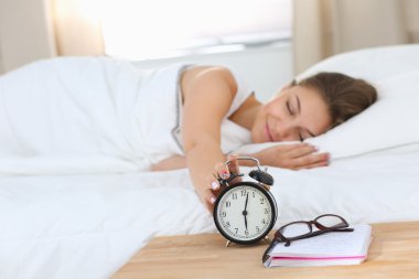 Genç bir kadın sabah alarmını erteliyor.