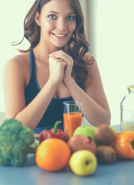 Mutfakta masada meyve suyu ve bardakla oturan bir kız.