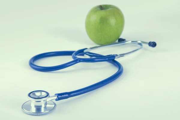 Medische stethoscoop en appel geïsoleerd op witte achtergrond — Stockfoto