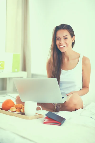 Young beautiful woman sitting in bed with laptop — Stock Photo, Image