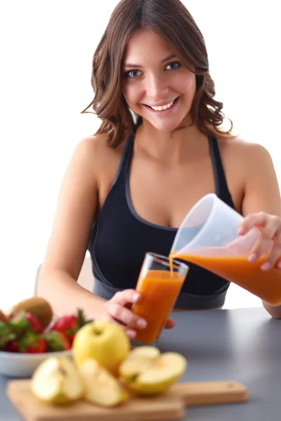 Chica sentada en la cocina en el escritorio con jugo de frutas y vasos —  Fotos de Stock