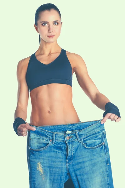 Junge Fitness-Frau zeigt, dass ihre alten Jeans — Stockfoto