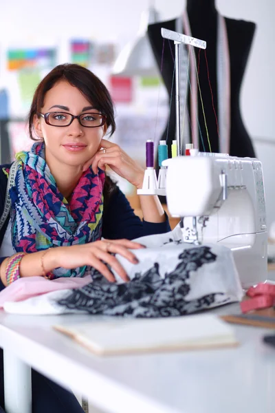 Jovem mulher costura enquanto sentado em seu local de trabalho — Fotografia de Stock