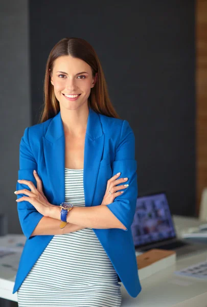 Porträt einer schönen Geschäftsfrau, die in der Nähe ihres Arbeitsplatzes steht — Stockfoto