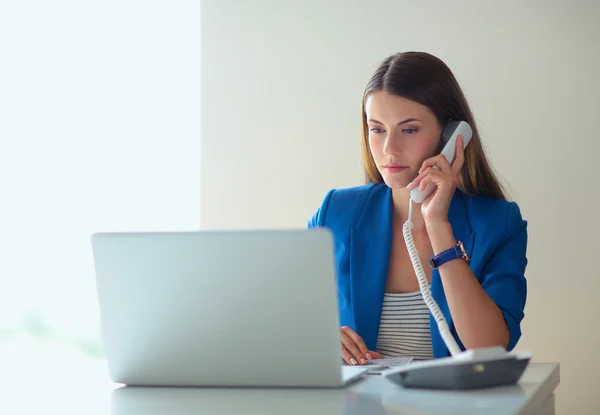 Portrait young woman on phone in front of a laptop computer