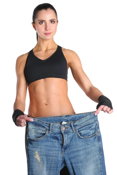 Junge Fitness-Frau zeigt, dass ihre alten Jeans — Stockfoto