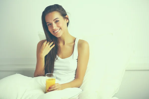 Wanita cantik berbaring di tempat tidur dengan gelas jus. — Stok Foto