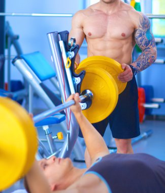 Genç adam eğitmen ile spor salonunda halter kaldırma