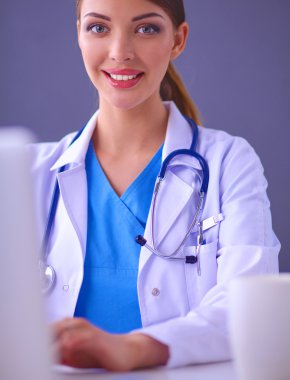 Gri arka planda oturan kadın doktor