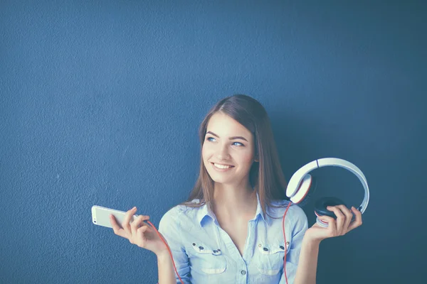 Lächelndes Mädchen mit Kopfhörern, das auf dem Boden neben der Wand sitzt — Stockfoto