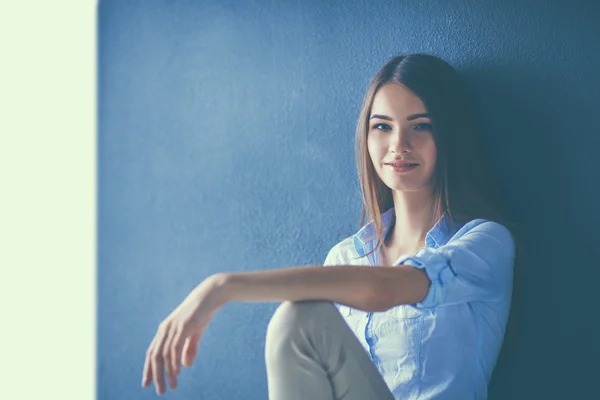 Mujer joven sentada en el suelo cerca de la pared oscura —  Fotos de Stock