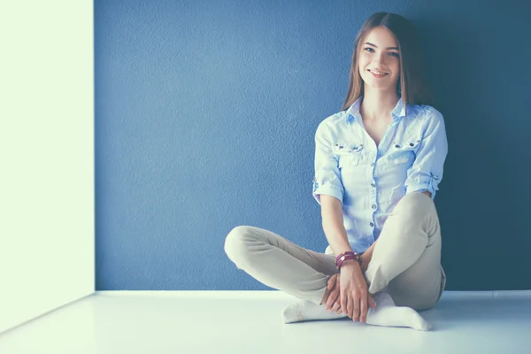 Young woman sitting on the floor near dark wall — Stock Photo, Image