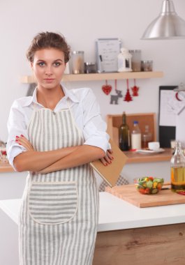 Mutfakta duran gülümseyen genç kadın.