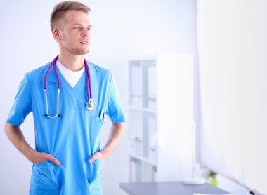 Steteskoplu doktor ayakta, çapraz kollu, beyaz arka planda izole.