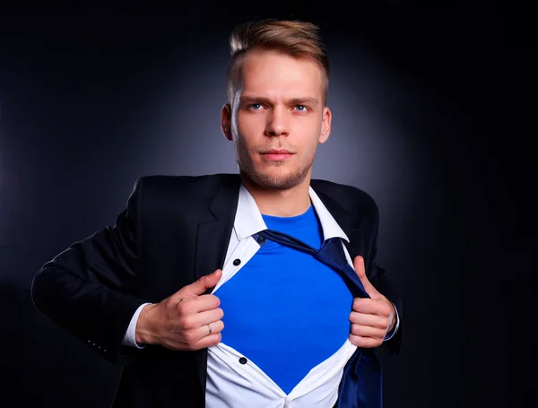 Joven hombre de negocios actuando como un súper héroe y rasgando su camisa, aislado sobre un fondo gris — Foto de Stock