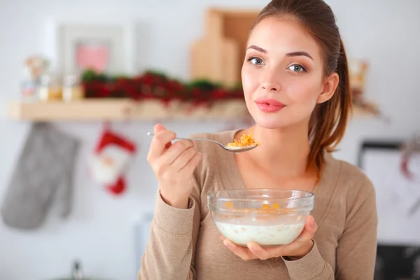 Giovane donna sorridente in piedi nella sua cucina — Foto Stock