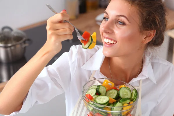 Mujer joven comiendo ensalada fresca en la cocina moderna — Foto de Stock