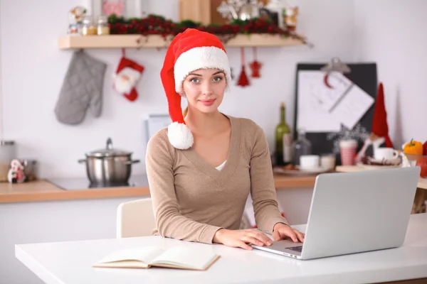 Mujer joven sonriente en la cocina, aislada en el fondo de Navidad —  Fotos de Stock