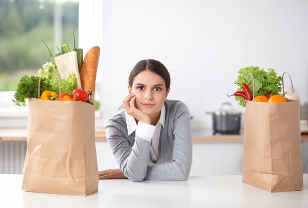 Giovane donna che tiene la spesa con verdure In piedi in cucina — Foto Stock