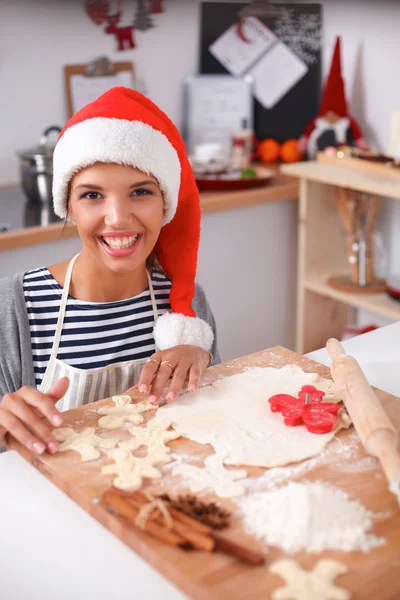 Gülümseyen genç bir kadın Noel hazırlıklarıyla eğleniyor Noel Baba şapkası takıyor — Stok fotoğraf