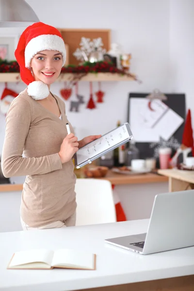 Lächelnde junge Frau in der Küche, isoliert auf weihnachtlichem Hintergrund — Stockfoto