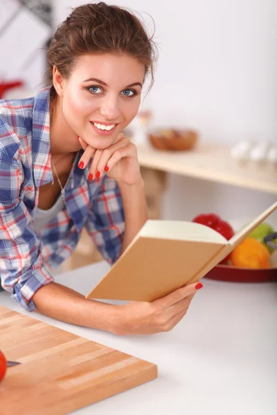 Ung kvinna läser kokbok i köket, letar efter recept — Stockfoto