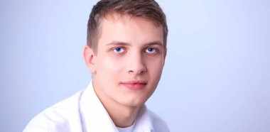 Gri arka plan üzerinde oturan gülümseyen genç adam portresi