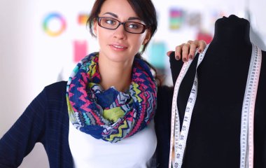 Gülümseyen moda tasarımcısı ofiste mankenin yanında duruyor.